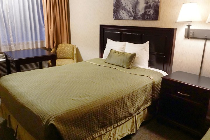 a bedroom with a bed and desk in a hotel room