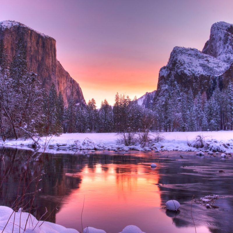 a lake surrounded by snow covered mountains in the background
